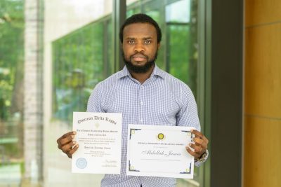 Abdullahi Jamiu holding two awards.